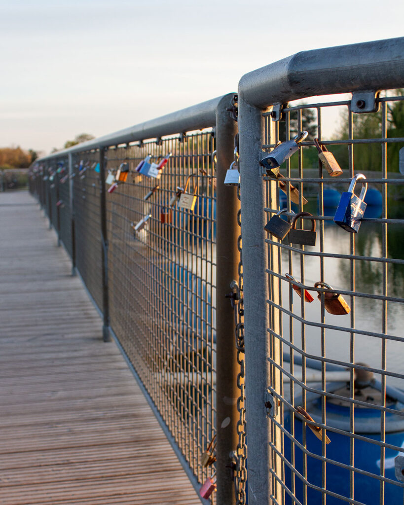 Liebesschlösser am Geländer einer Stegbrücke im Abendlicht